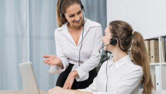 Two female desk agents talking with each other.