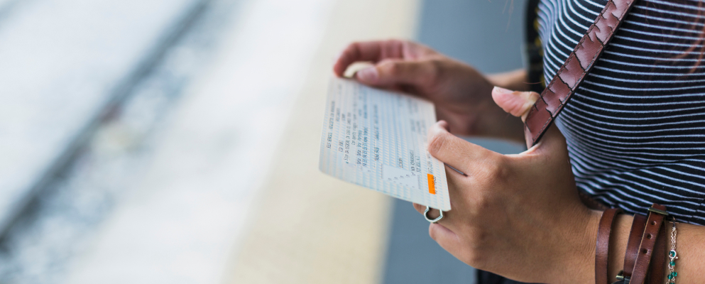 A female tourist holding a card while waiting on a sideway.