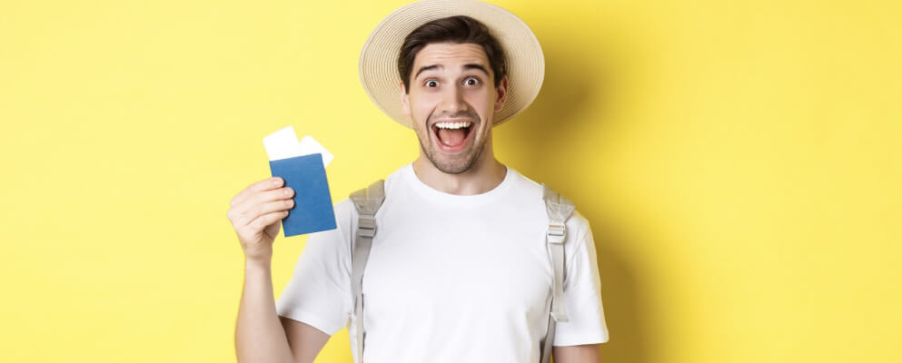 A male tourist smiling at the camera while holding a passport.