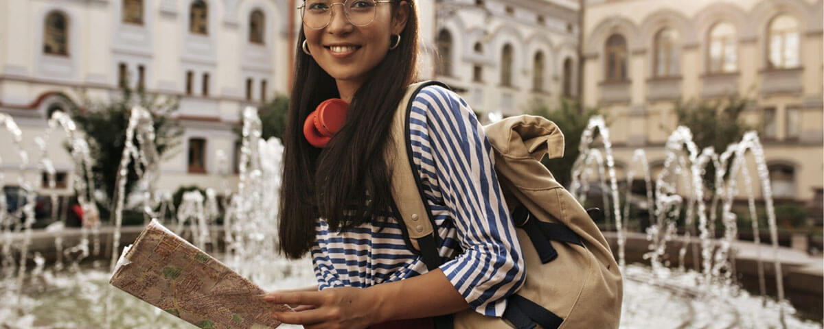 A female tourist holding a map beside a fountain