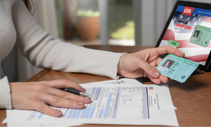 A female sitting at a table and holding green card and a ballpen