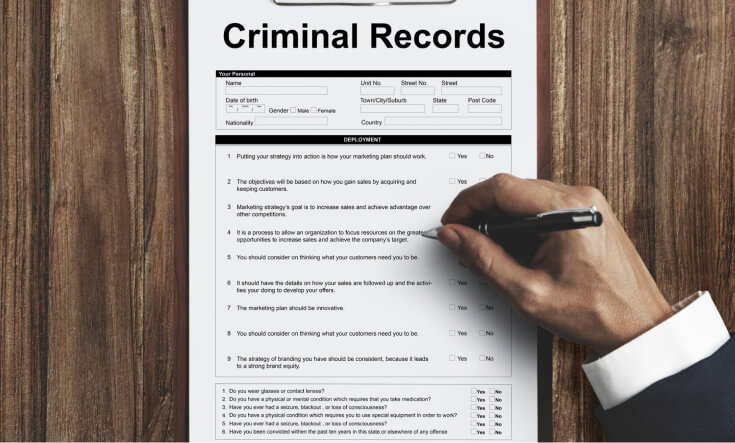A form of Criminal Records being filled up on a wooden table