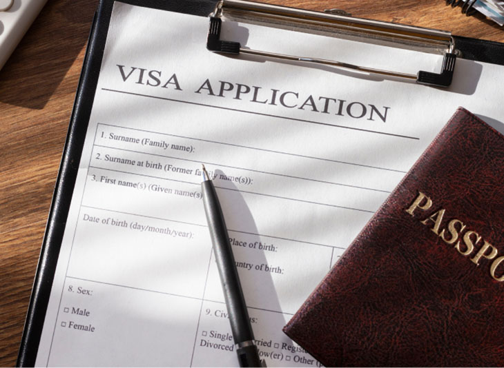 A visa application form with a black ball pen and a passport over it.
