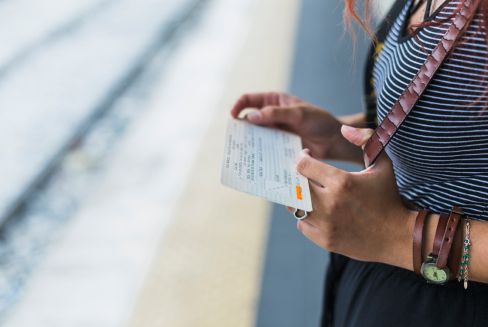 A female tourist holding a card while waiting on a sideway.