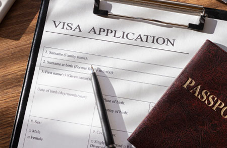 A visa application form with a black ball pen and a passport over it.