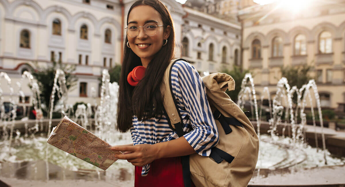 A female tourist holding a map beside a fountain