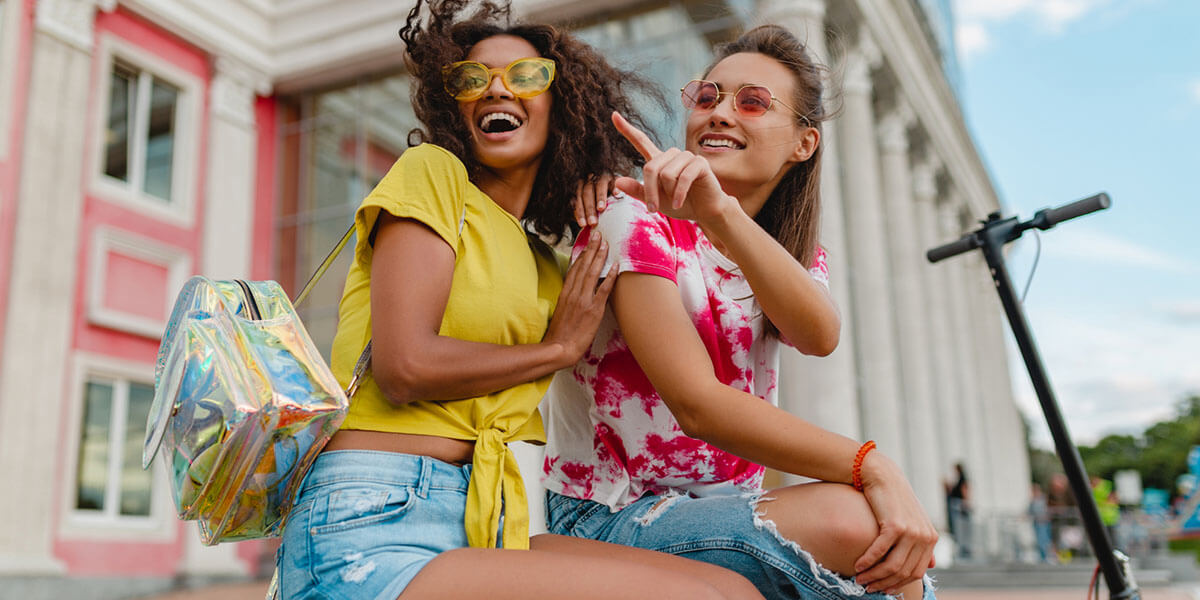 Two happy female tourists sitting outside the building.